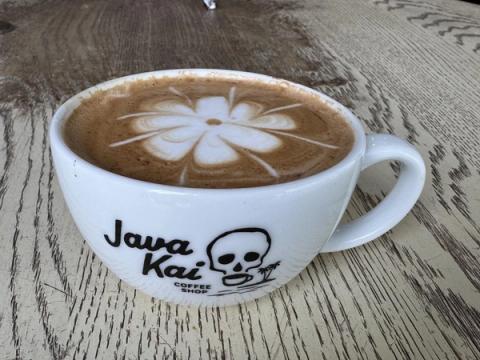 Artfully crafted latte with hibiscus flower foam art in a Java Kai branded cup