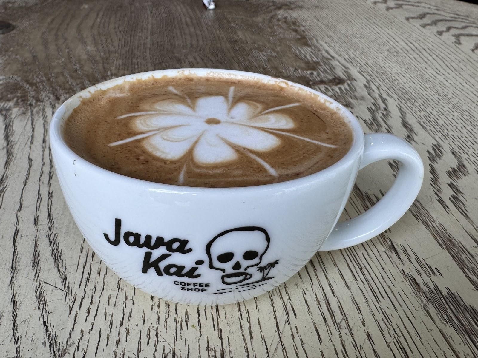 Artfully crafted latte with hibiscus flower foam art in a Java Kai branded cup