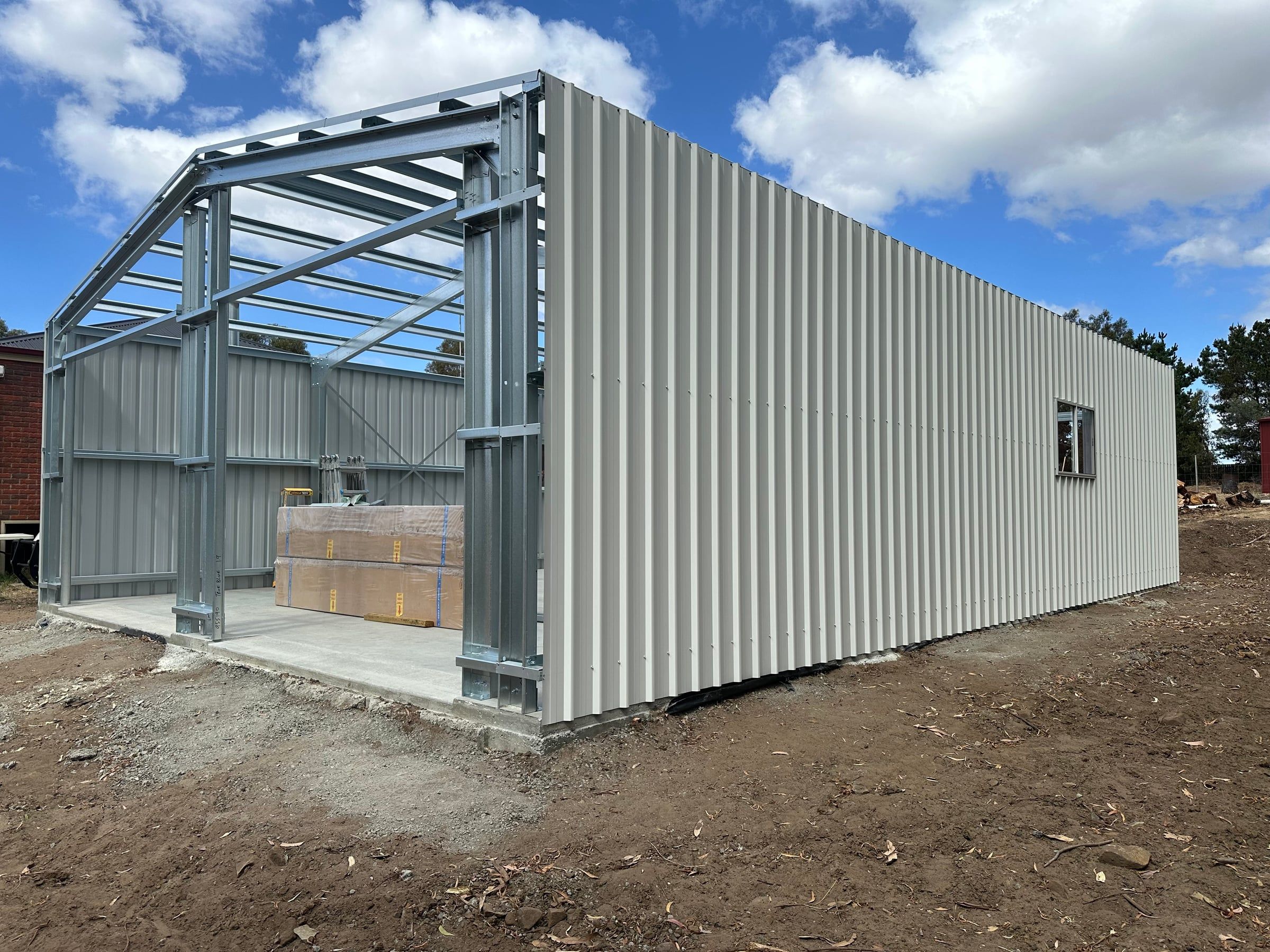 Steel frame going up for the Pontville garage, with the side wall clad and the front still open