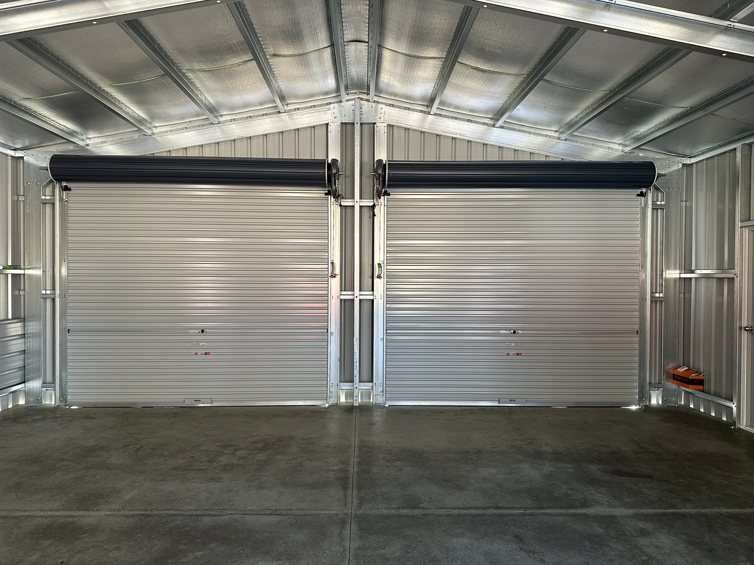 Both roller doors from inside the garage, above a smooth concrete slab