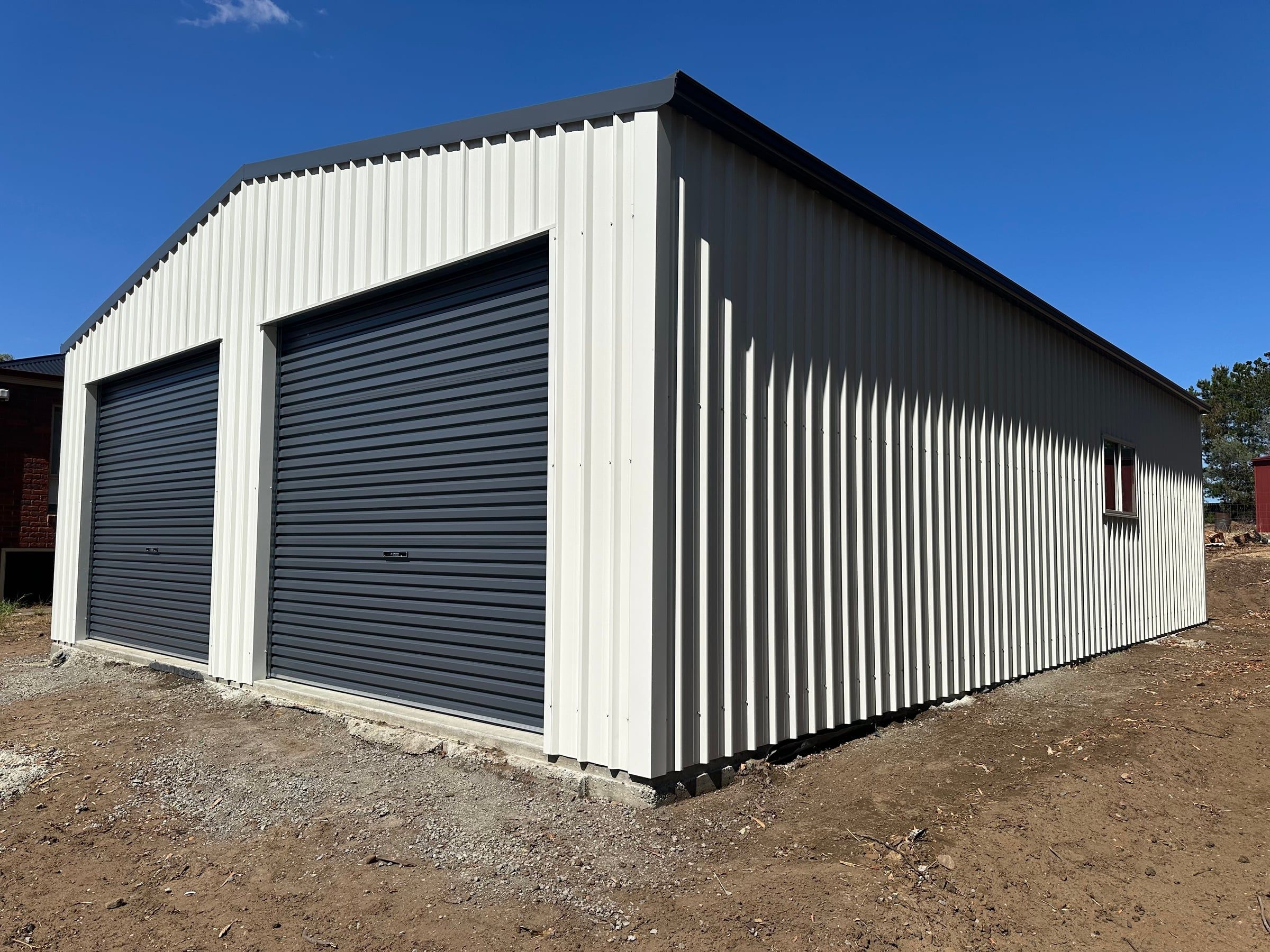 Finished Pontville garage from the front corner, with Ironstone roller doors and Surfmist walls