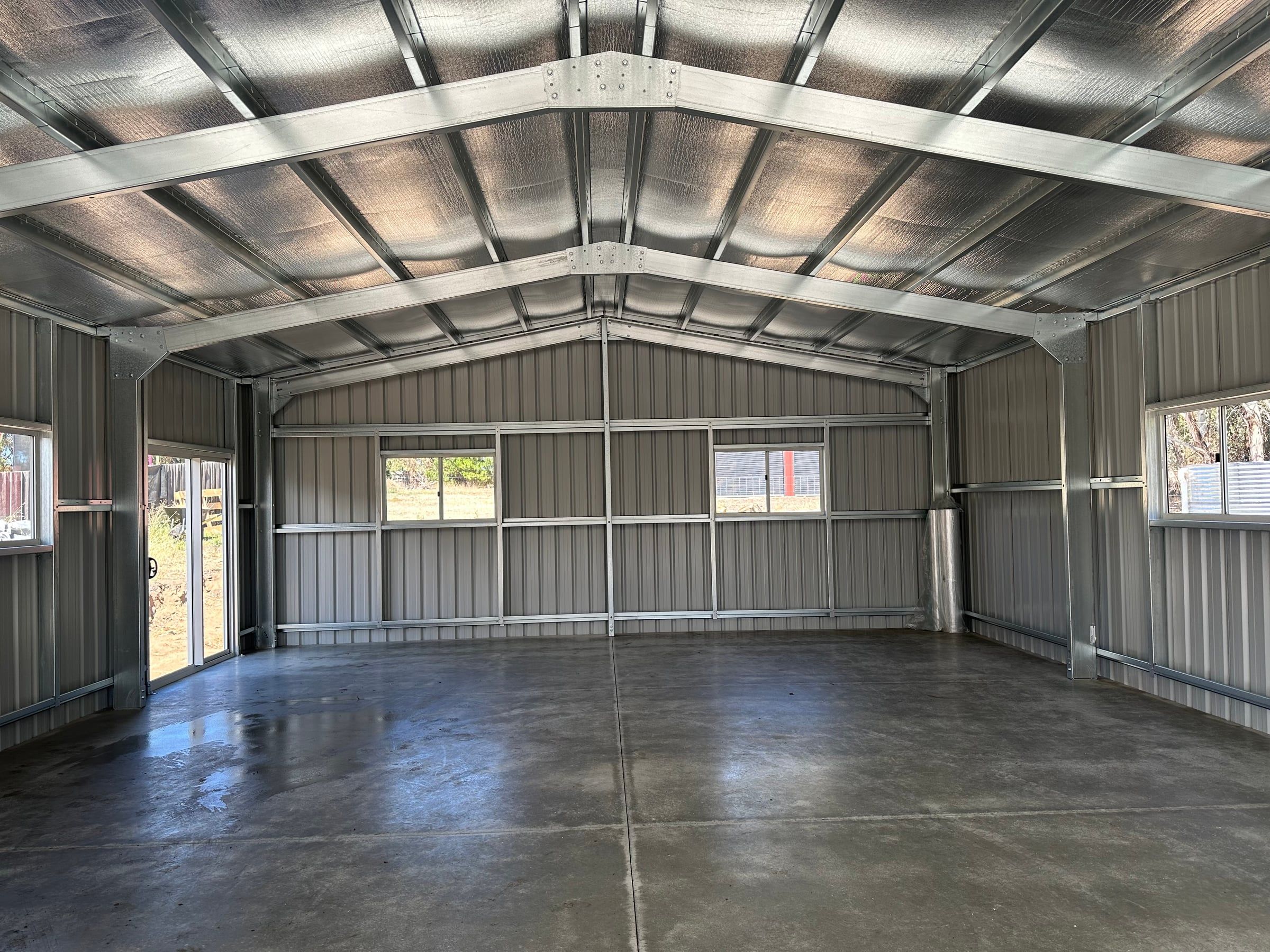 Inside the clear-span garage, looking up at the portal frames and roof purlins
