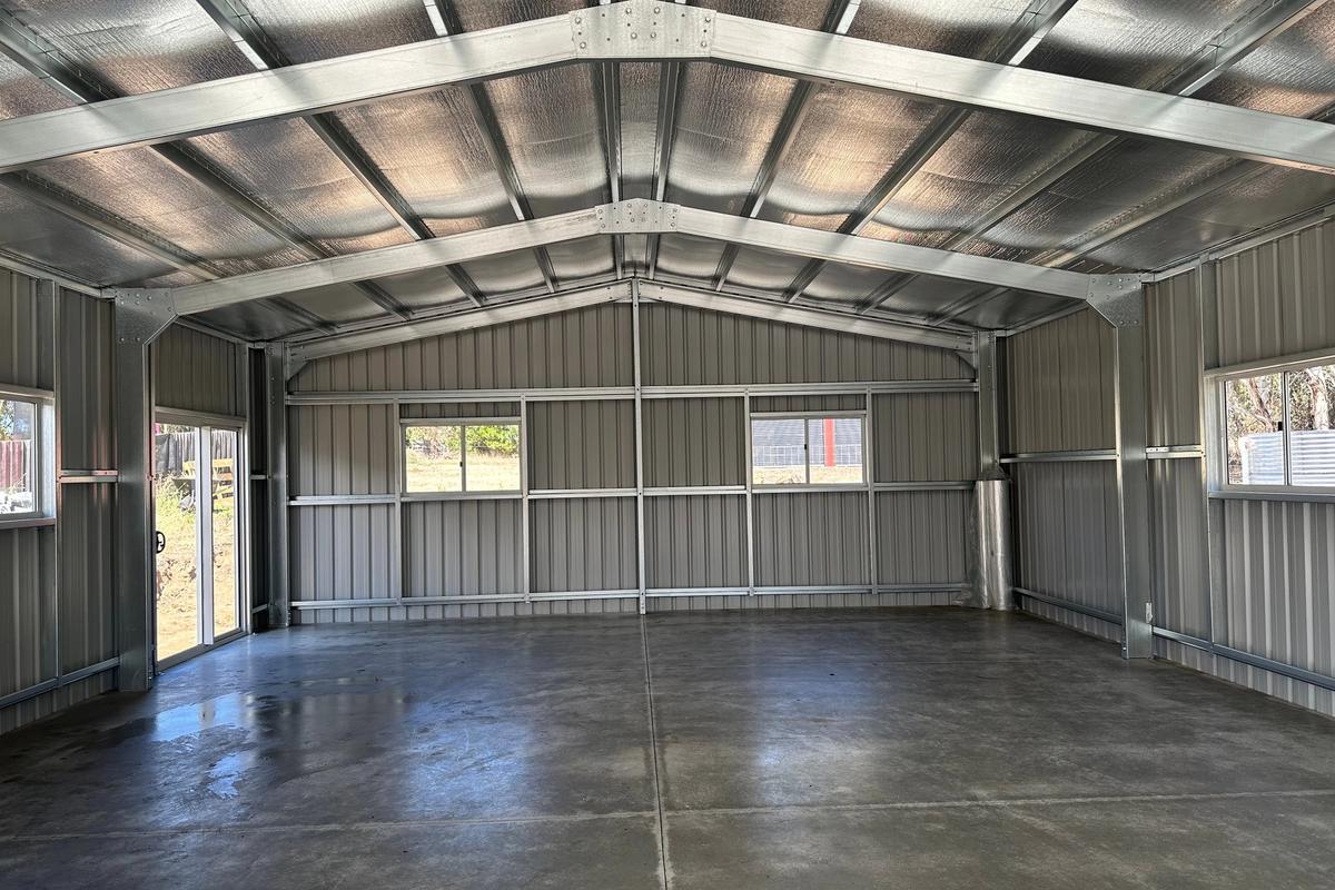 Inside the clear-span garage, looking up at the portal frames and roof purlins