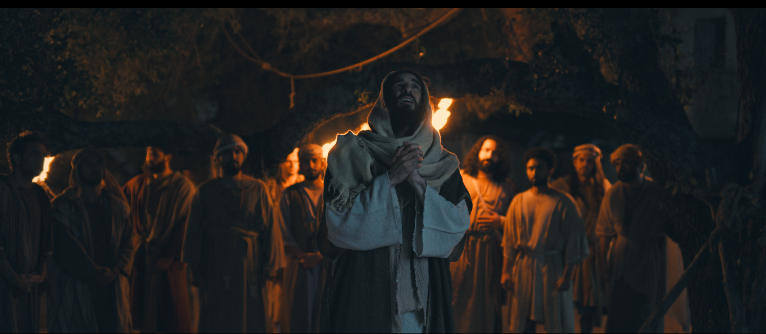 Jesus prays at night, His disciples gathered behind Him