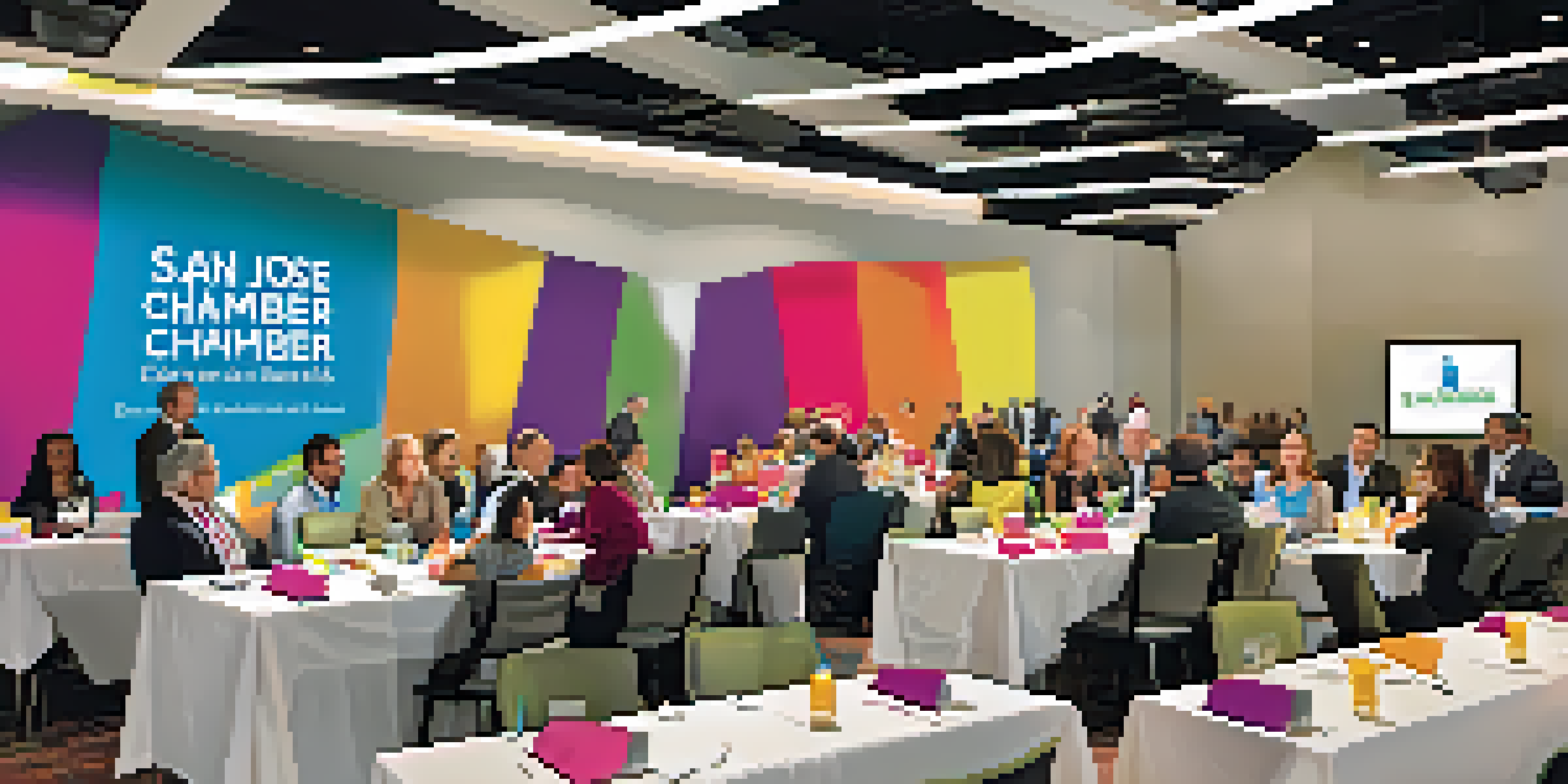 A colorful networking event with diverse professionals talking and exchanging business cards in a bright conference hall.