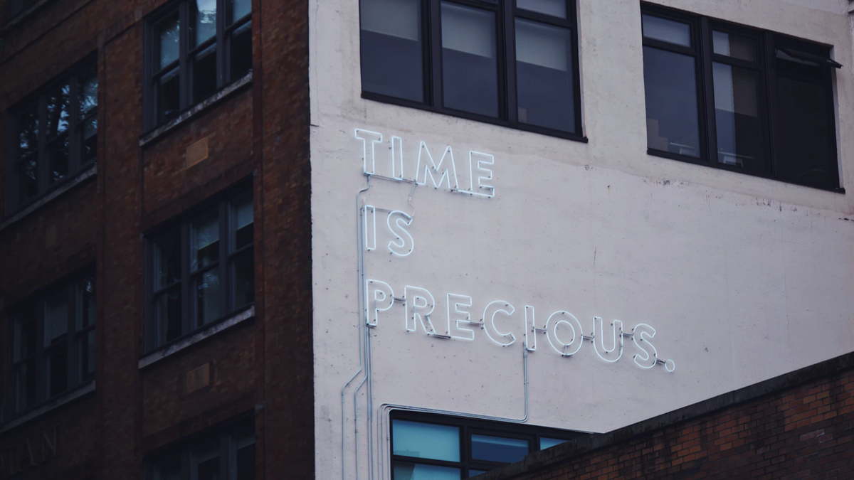 A building with a neon sign reading Time Is Precious