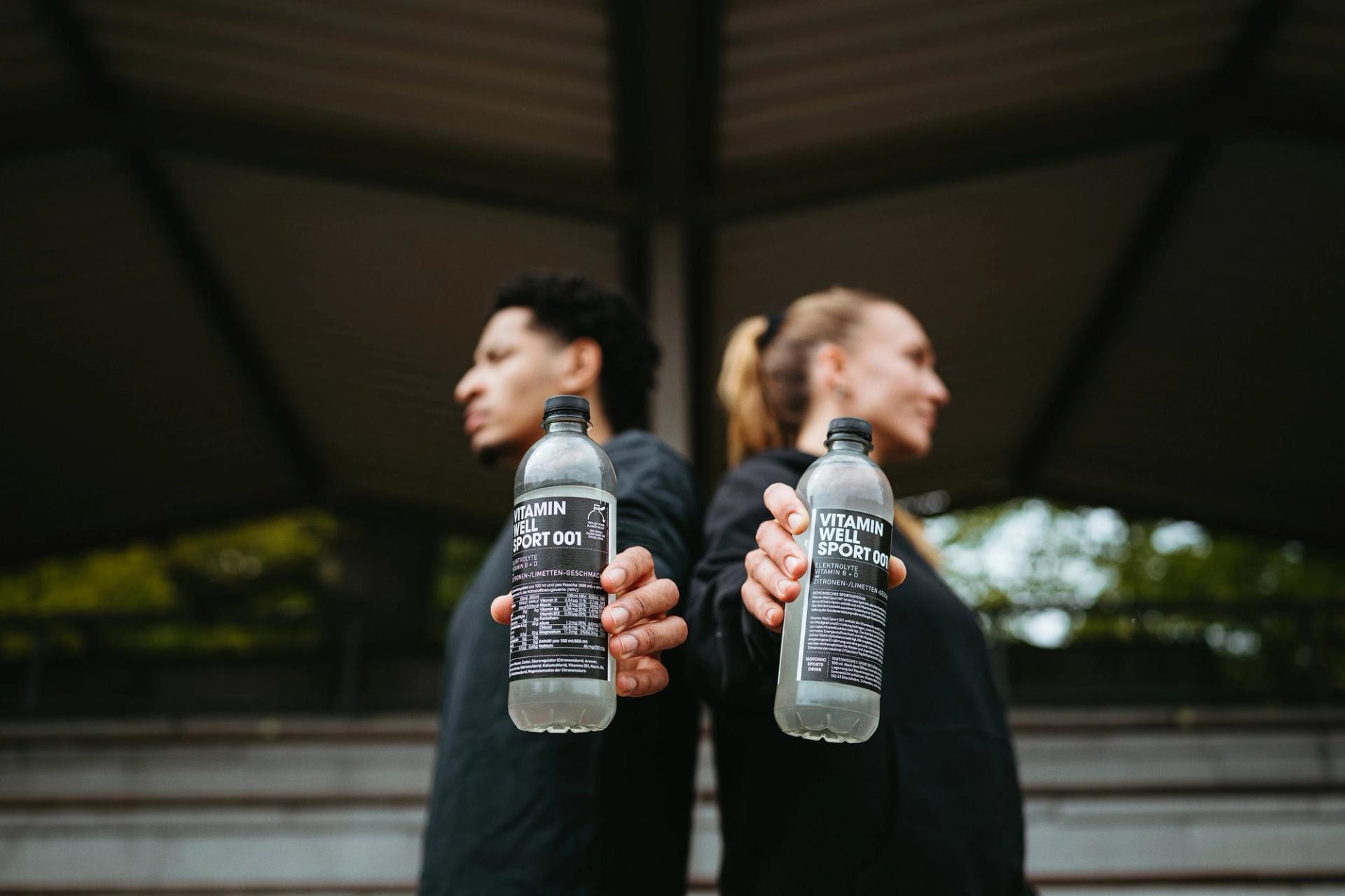 Two athletes holding out Sport 001 bottles toward camera — Björn Lexius, Hamburg