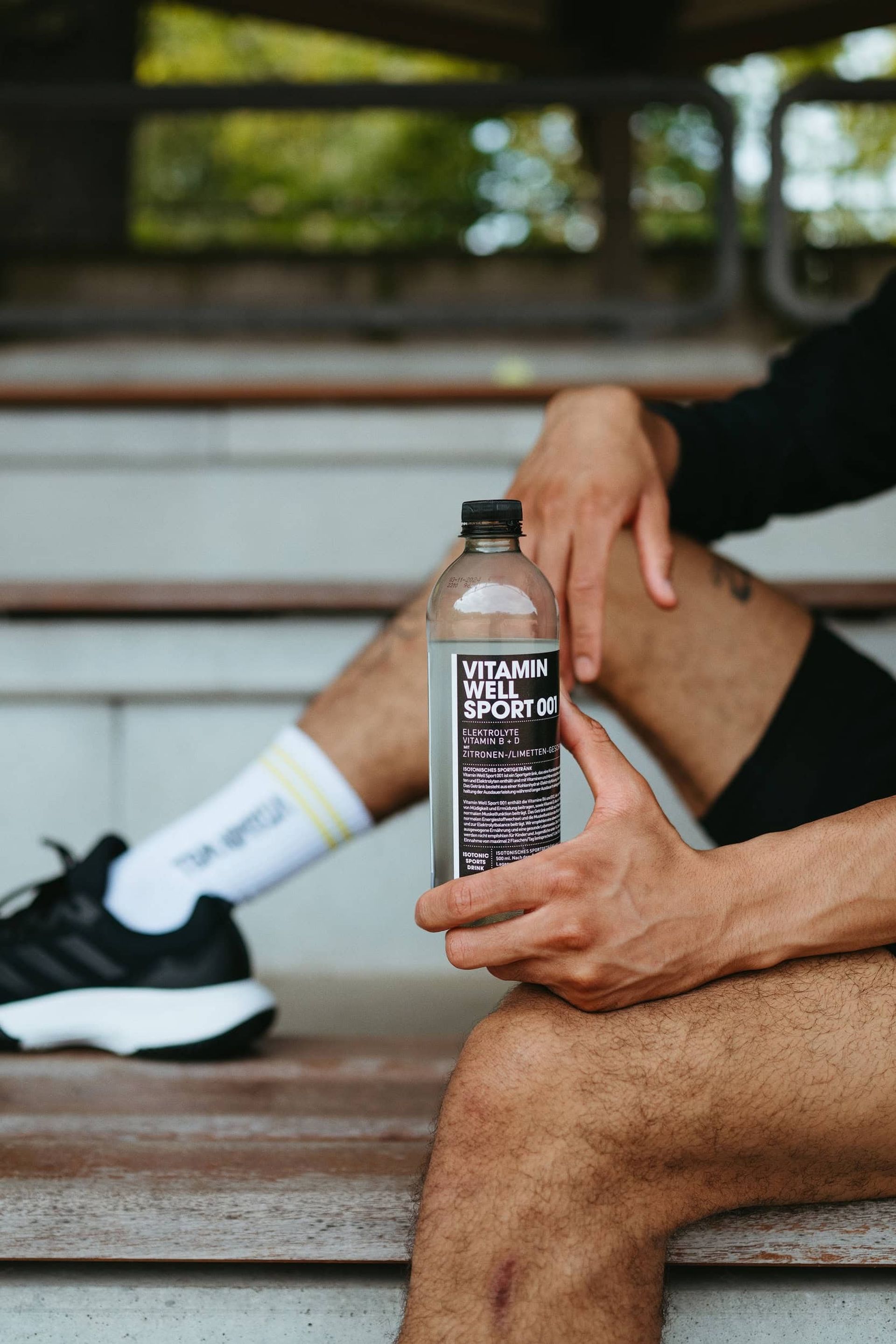 Close-up of hands holding Sport 001 bottle on a bench — Björn Lexius, Hamburg