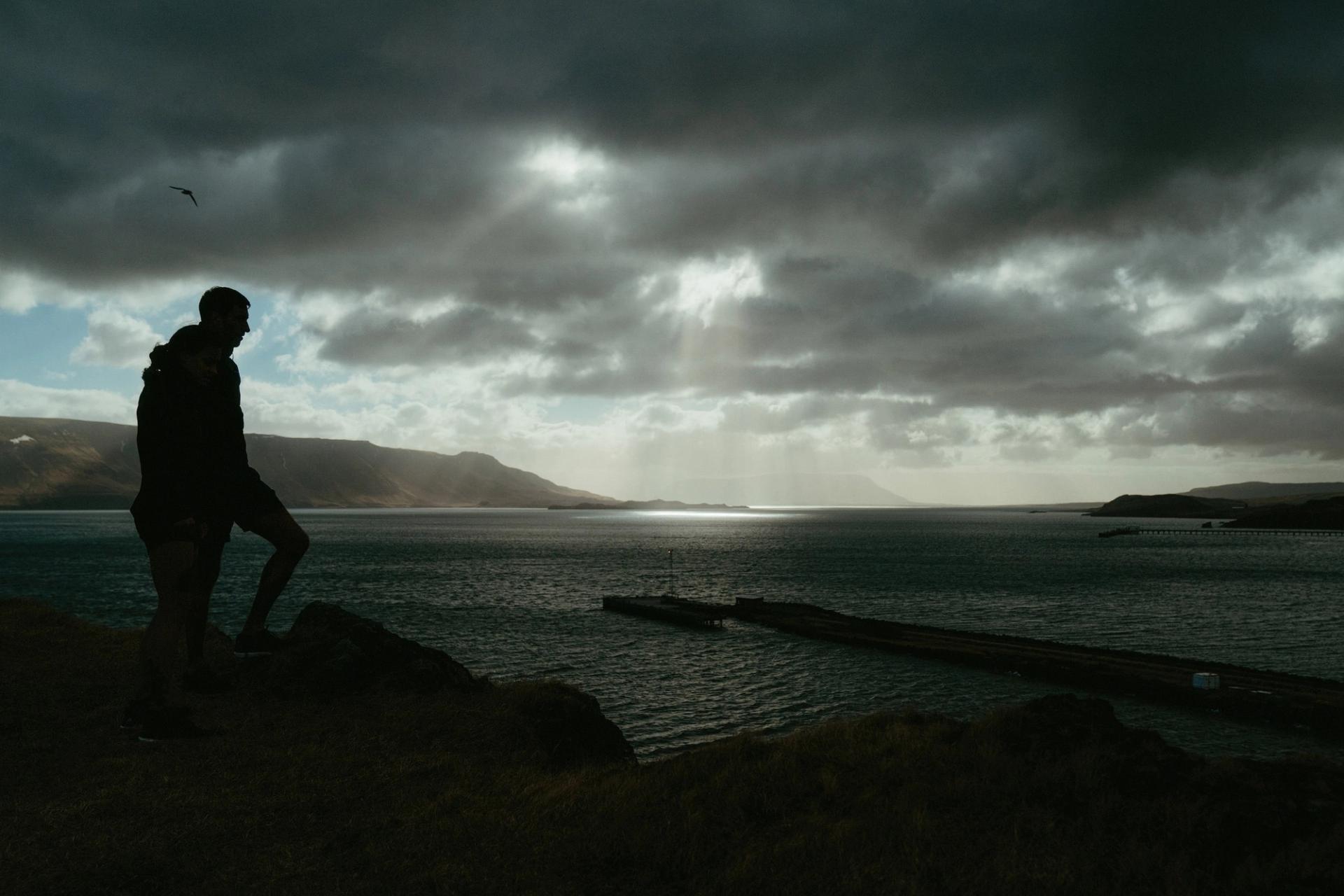 Silhouette of two runners against a fjord at dusk — Björn Lexius, Iceland