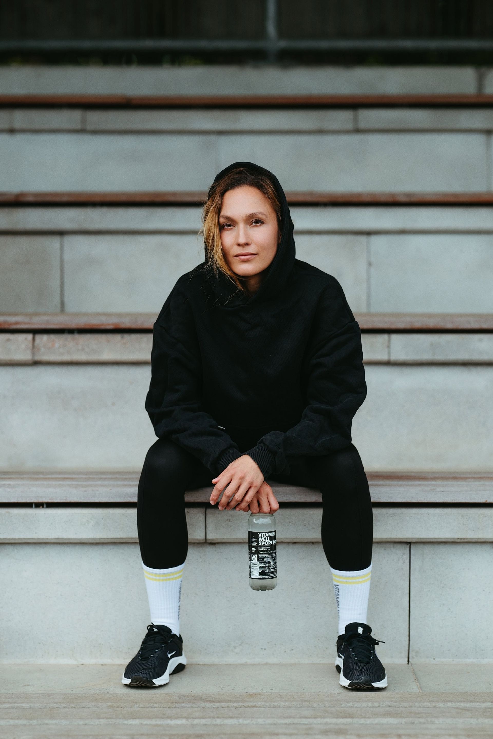 Athlete in black hoodie on stadium steps holding Sport 001 — Björn Lexius, Hamburg