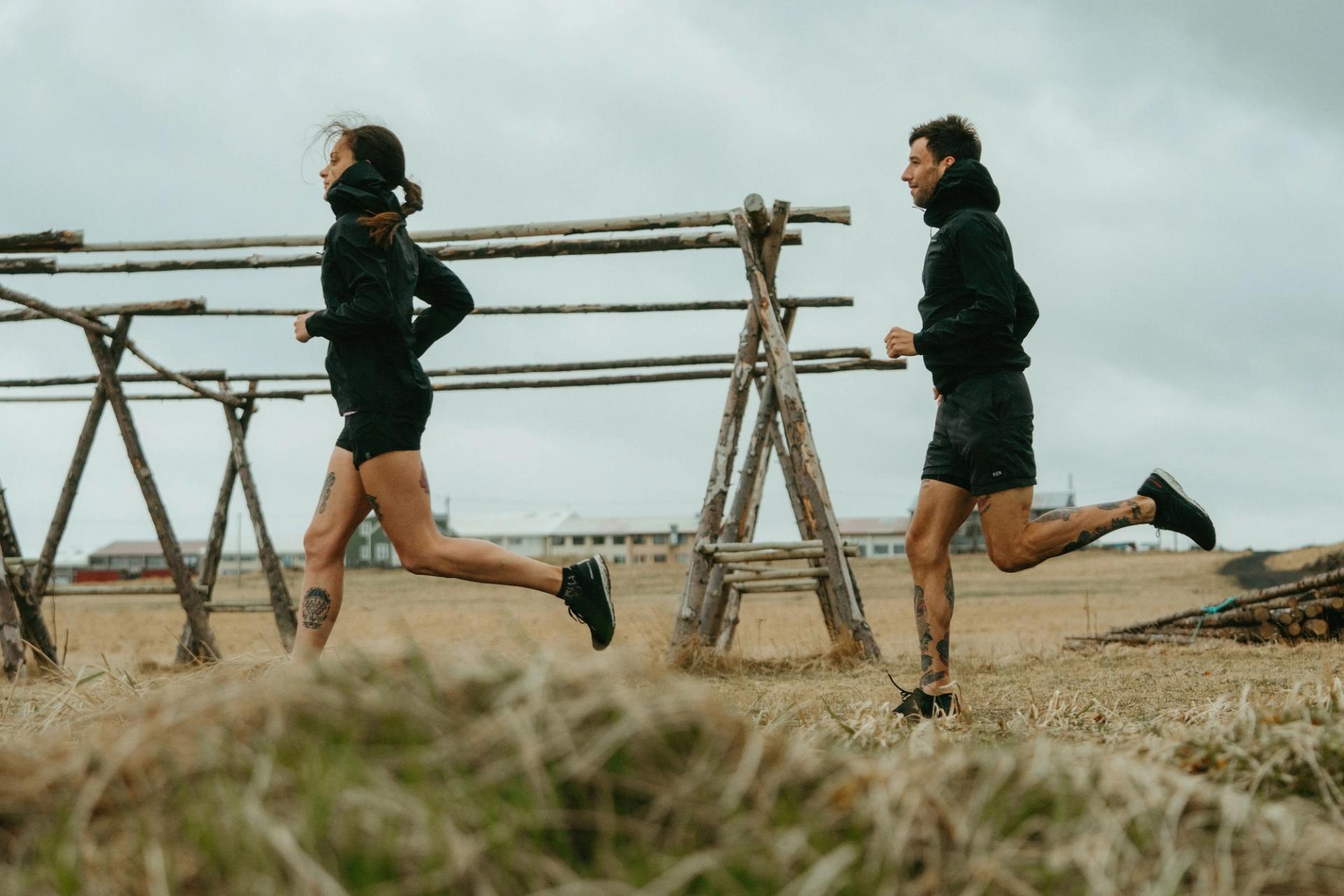 Two runners jogging past traditional wooden fish-drying racks — Björn Lexius, Iceland