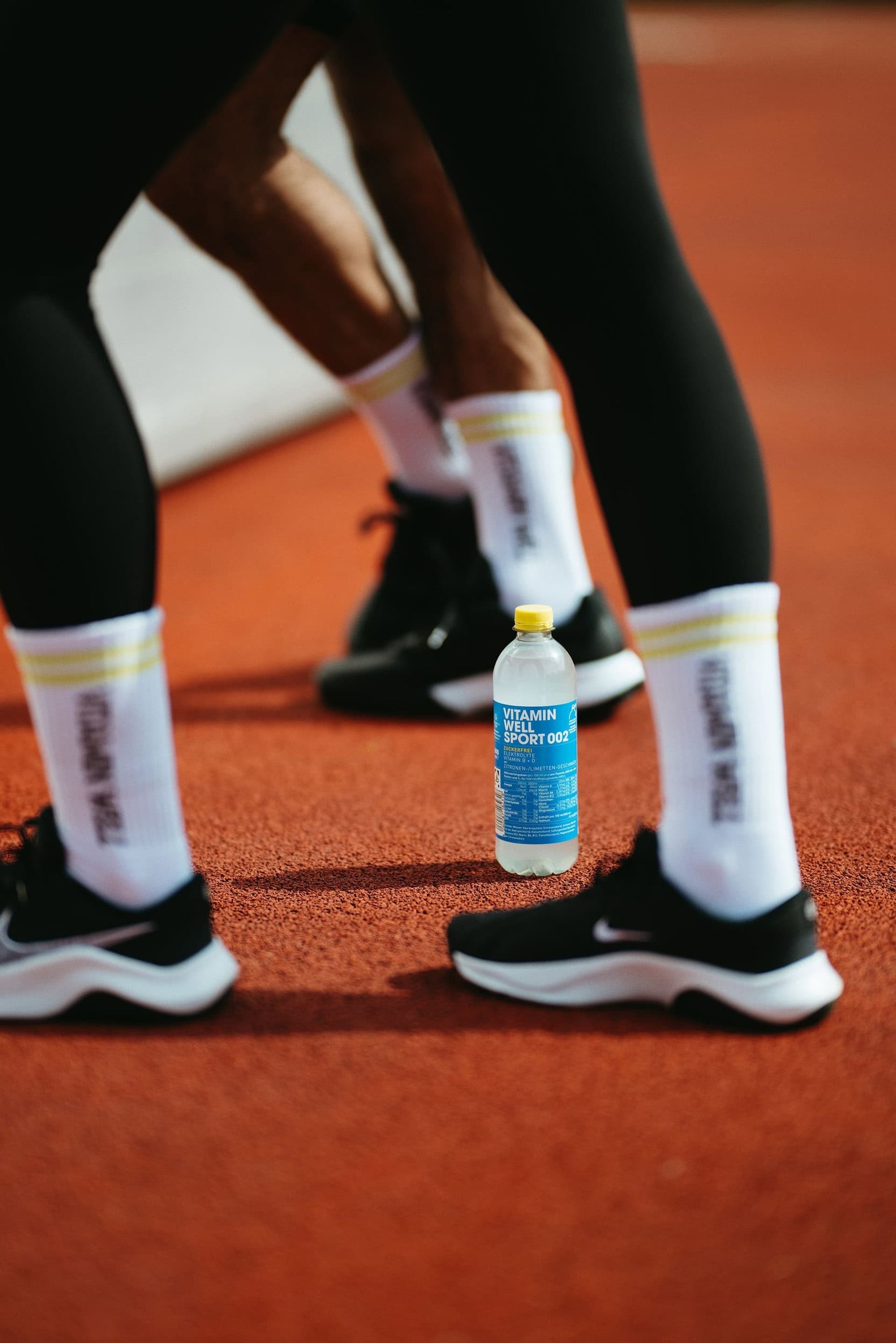 Runner's legs with Vitamin Well socks and Sport 002 bottle on track — Björn Lexius, Hamburg