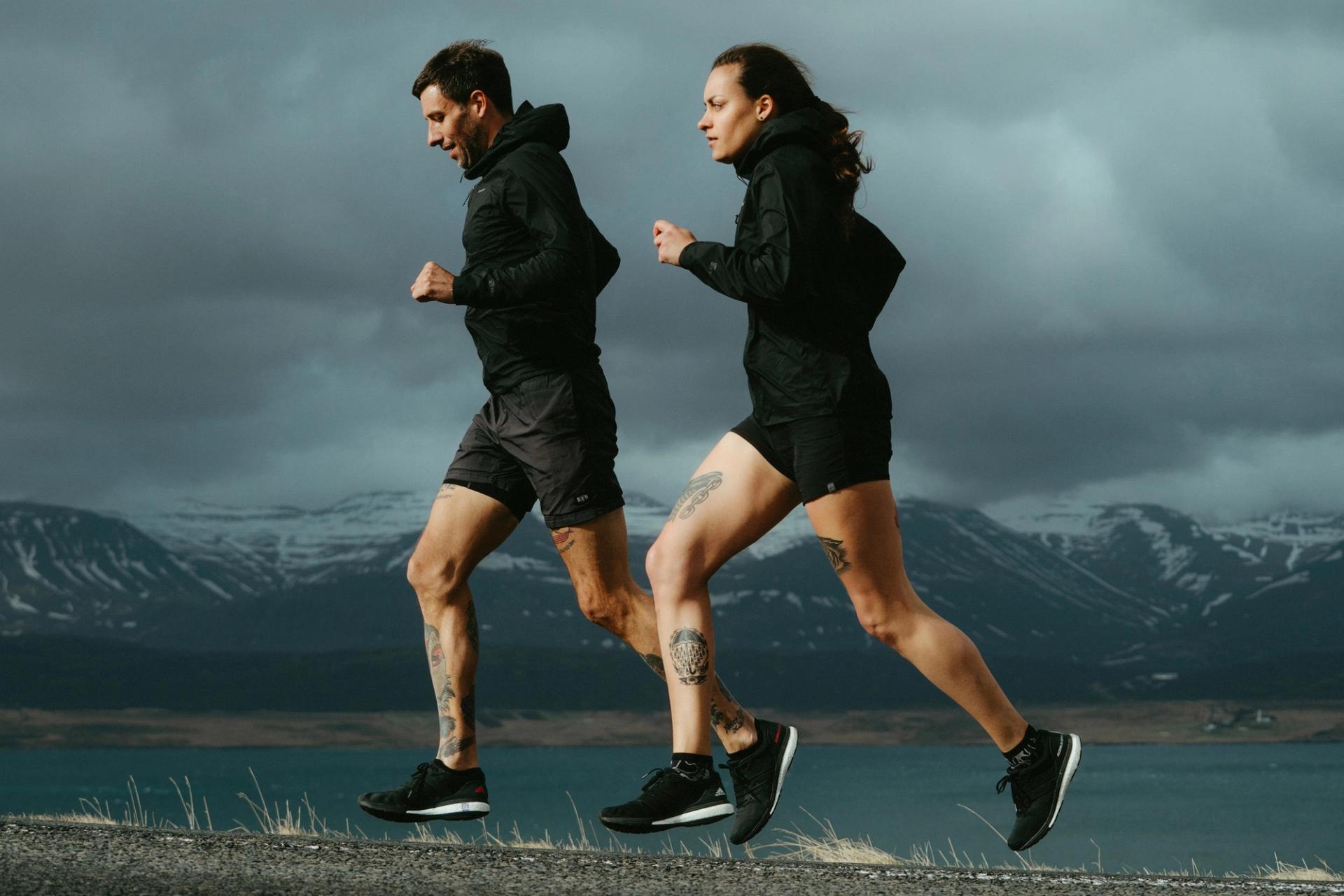 Two runners jogging side by side with a lake and mountains behind — Björn Lexius, Iceland