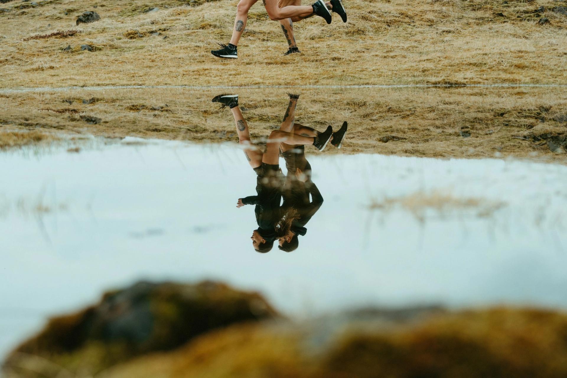 Reflection of two runners in a roadside puddle — Björn Lexius, Iceland