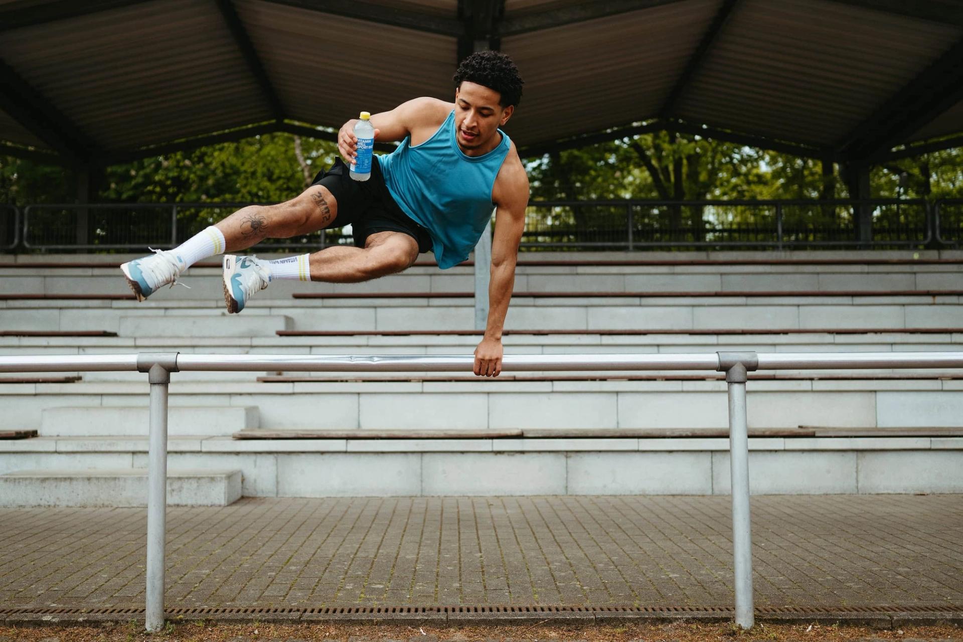 Athlete vaulting over a railing holding Sport 002 bottle mid-air — Björn Lexius, Hamburg
