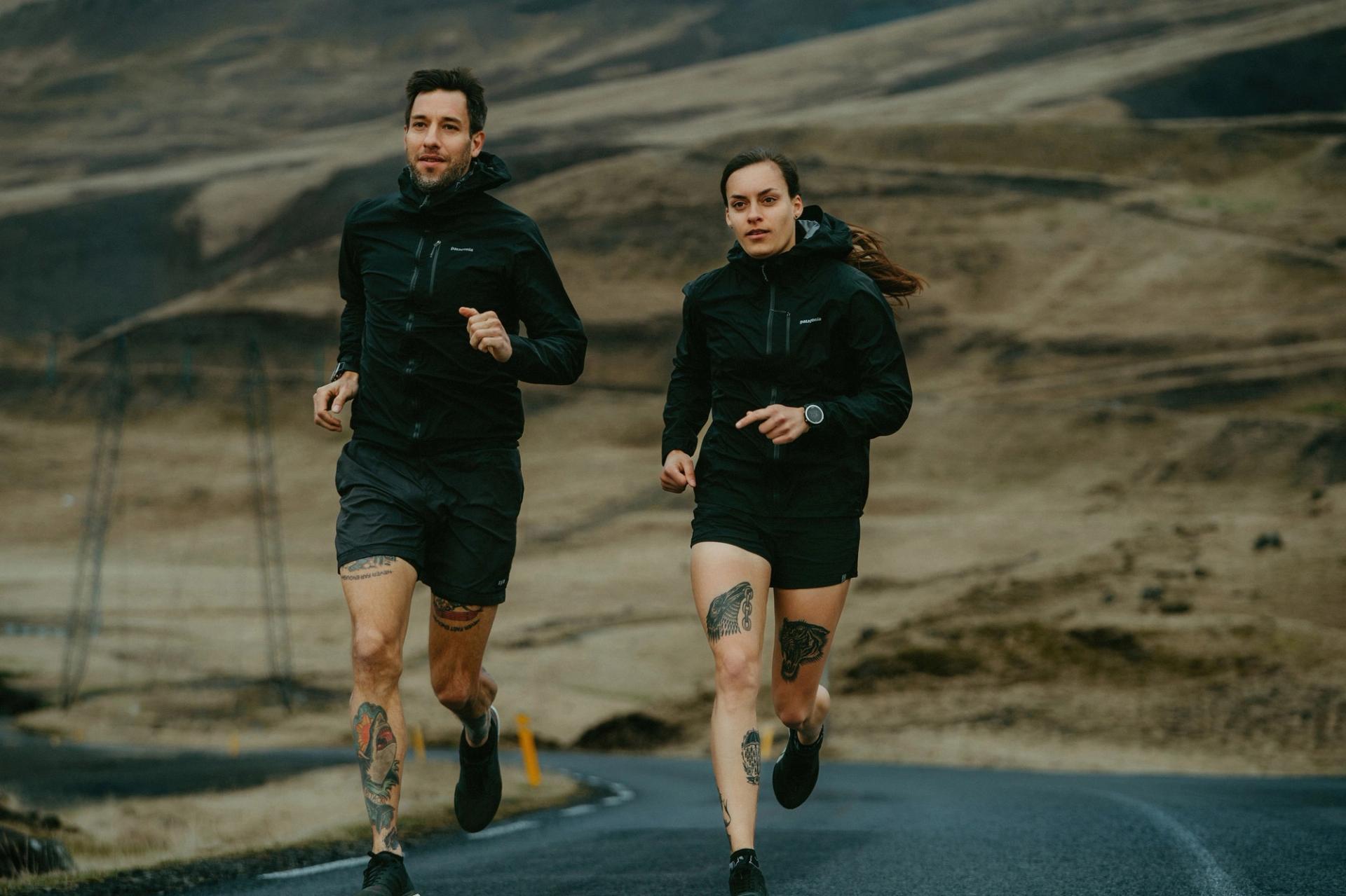 Two runners jogging on a mountain road, tattoos visible — Björn Lexius, Iceland