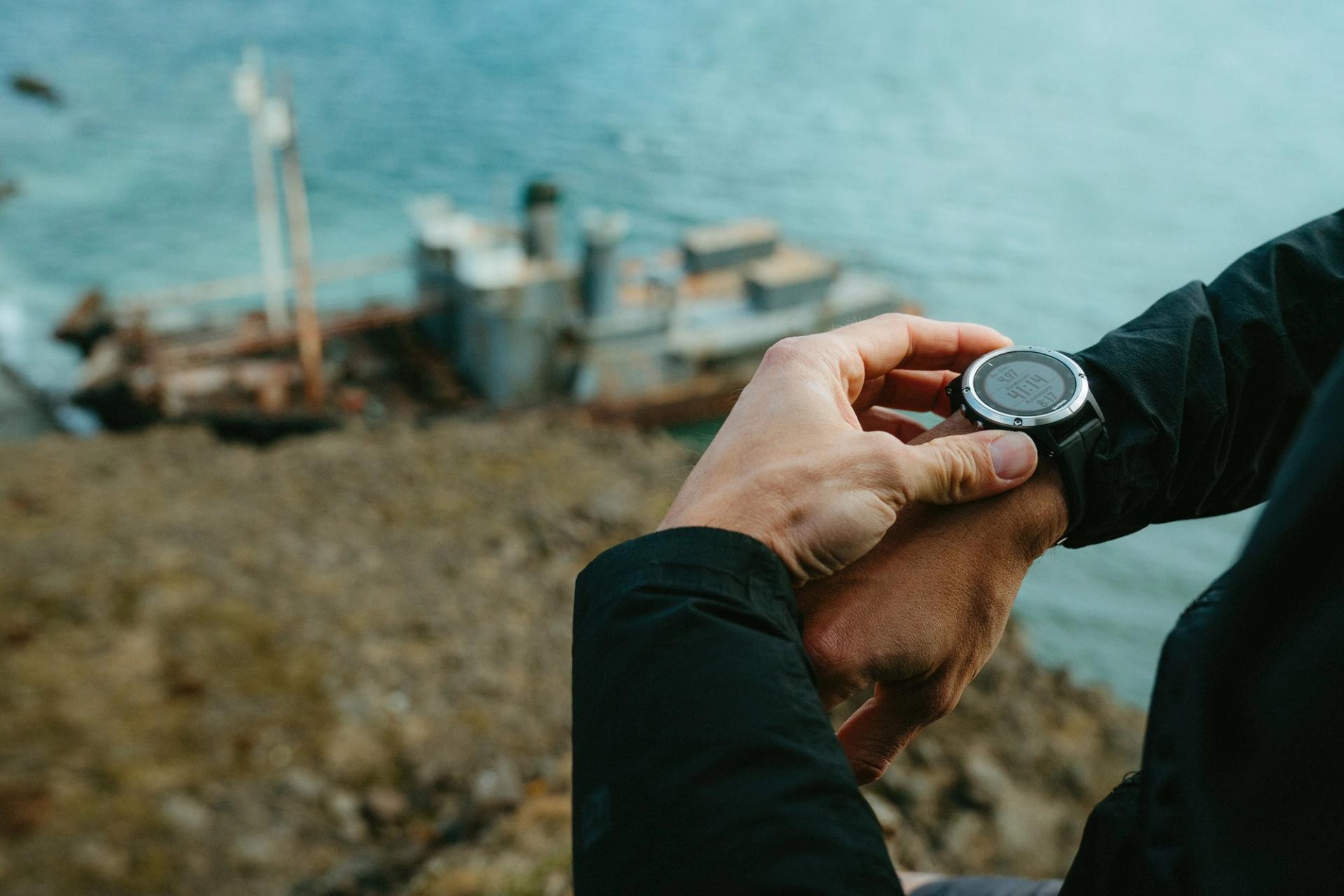Close-up of a runner checking his GPS watch by a shipwreck — Björn Lexius, Iceland
