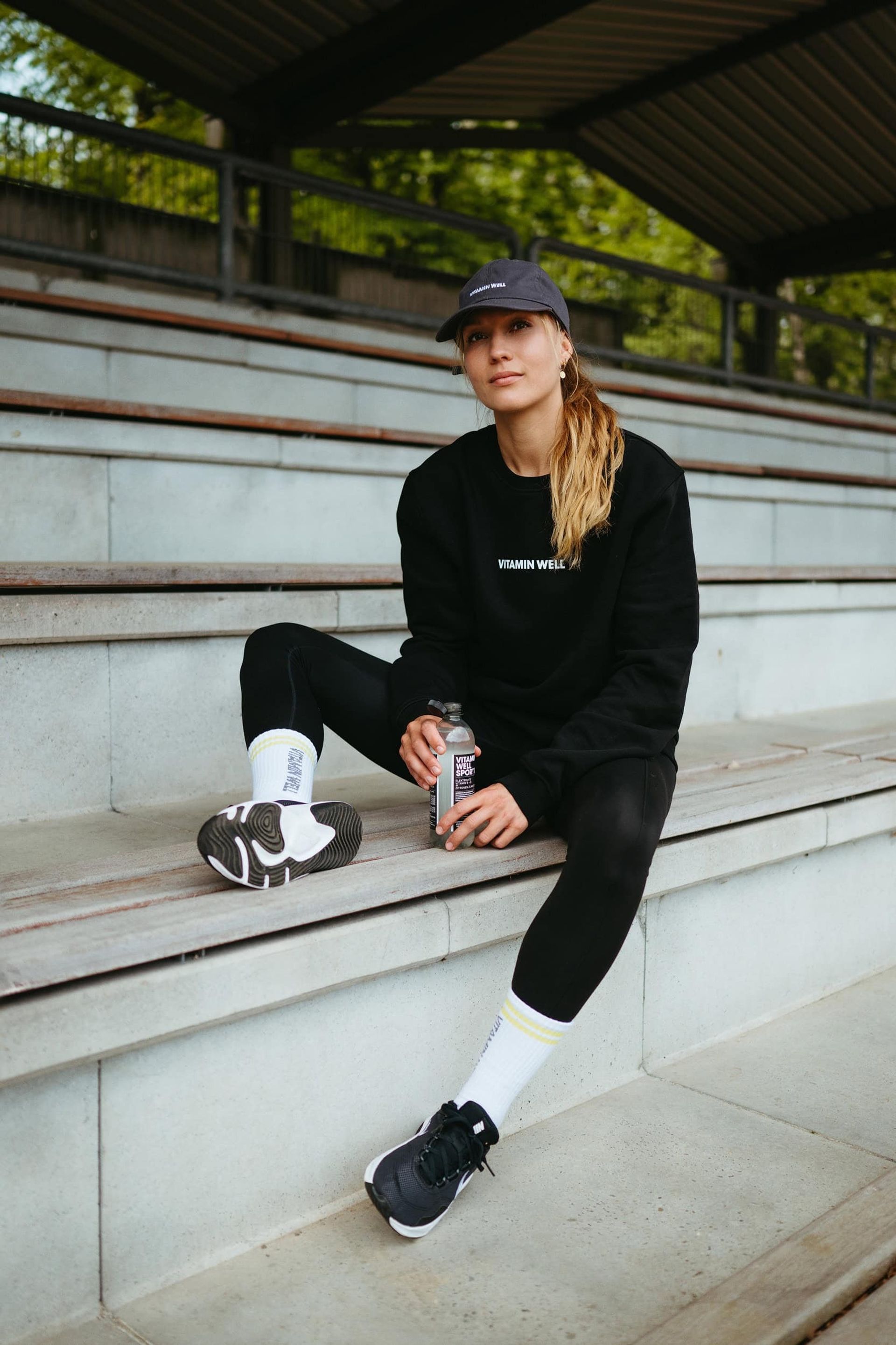 Hand holding Sport 001 bottle on stadium bench — Björn Lexius, Hamburg