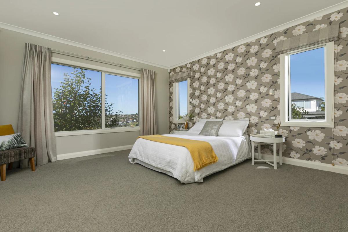 Bedroom with feature floral wallpaper and windows to the garden