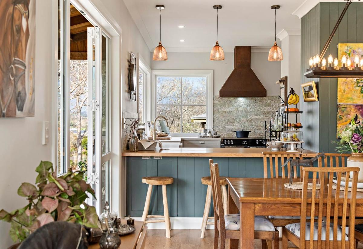 Kitchen with a blue painted island, copper range hood and pendant lighting