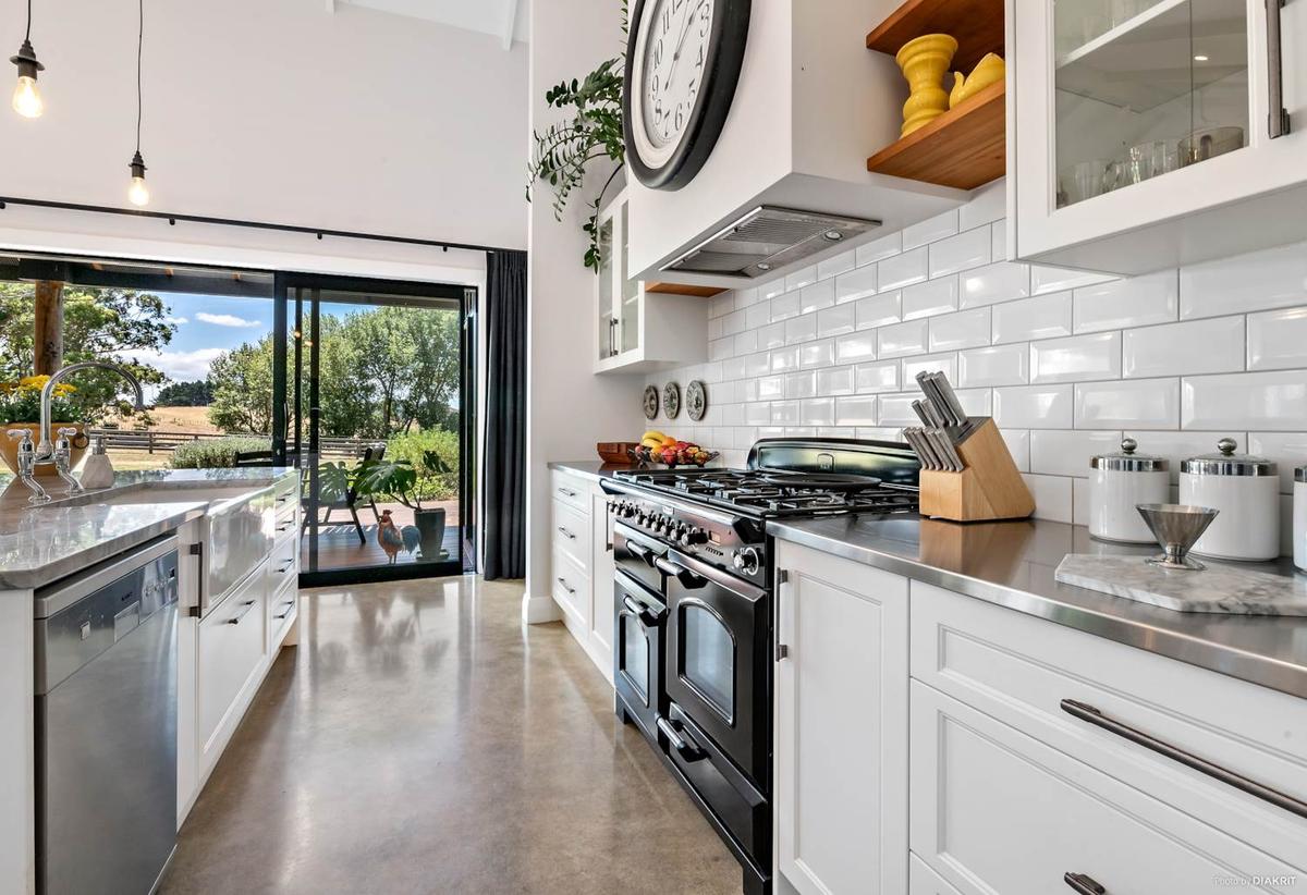 Kitchen with white subway tiles, a black range and polished concrete floor