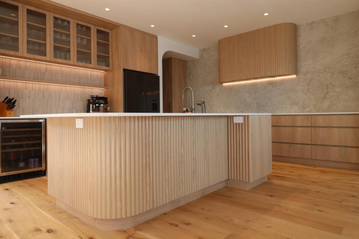 Curved fluted island bench in oak, with glass fronted display cabinetry