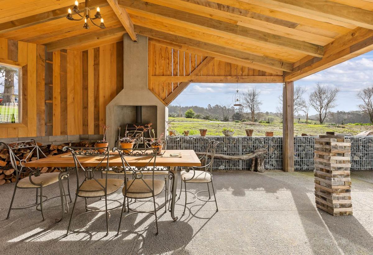 Covered outdoor room with exposed timber rafters and a built in fireplace