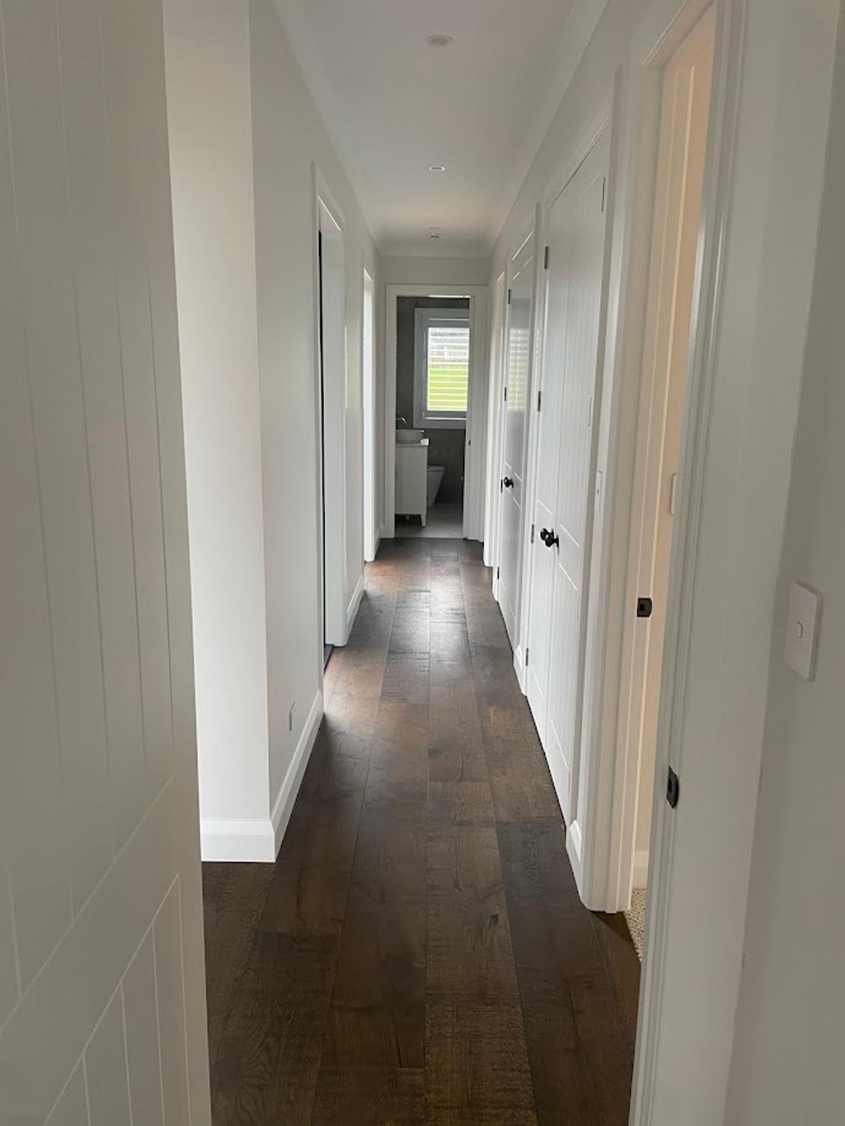Hallway with dark timber flooring and white panelled walls
