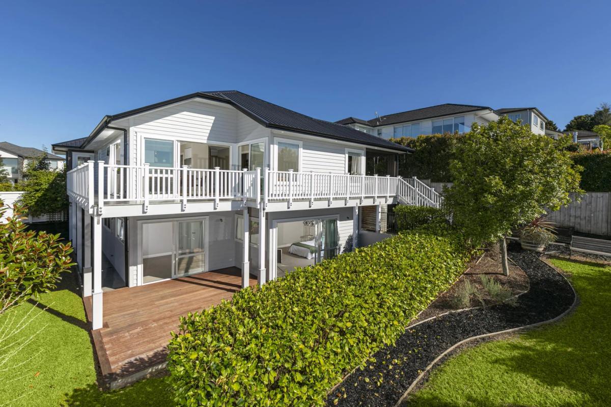 White weatherboard exterior with a wraparound deck and painted balustrade