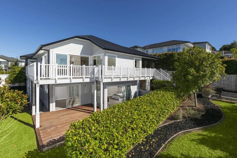 White weatherboard exterior with a wraparound deck and painted balustrade