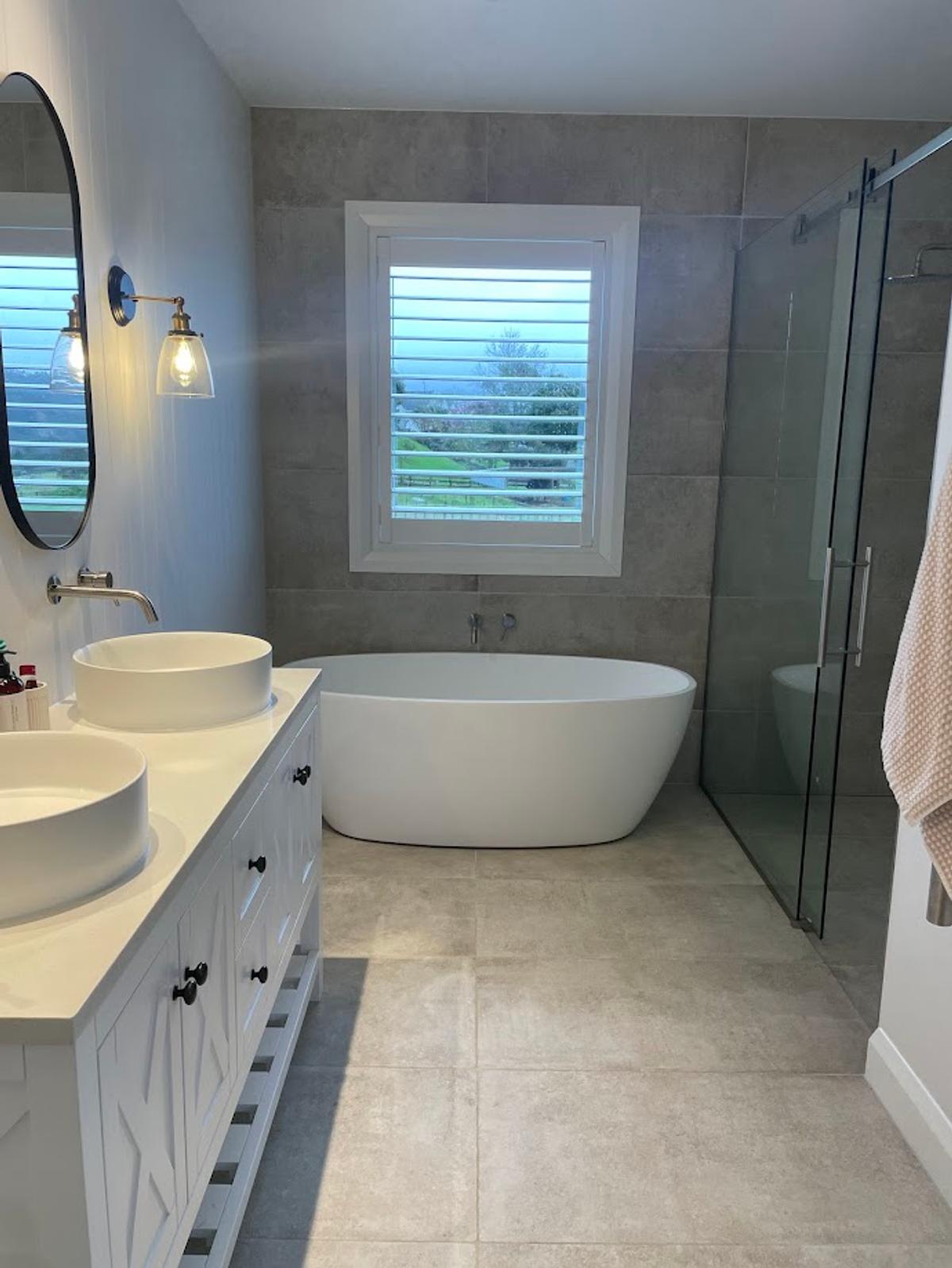 Bathroom with a freestanding bath, double vanity and grey tiled walls