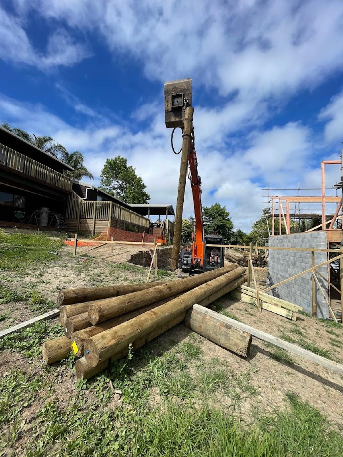 Pile driver at work, with timber piles stacked on site
