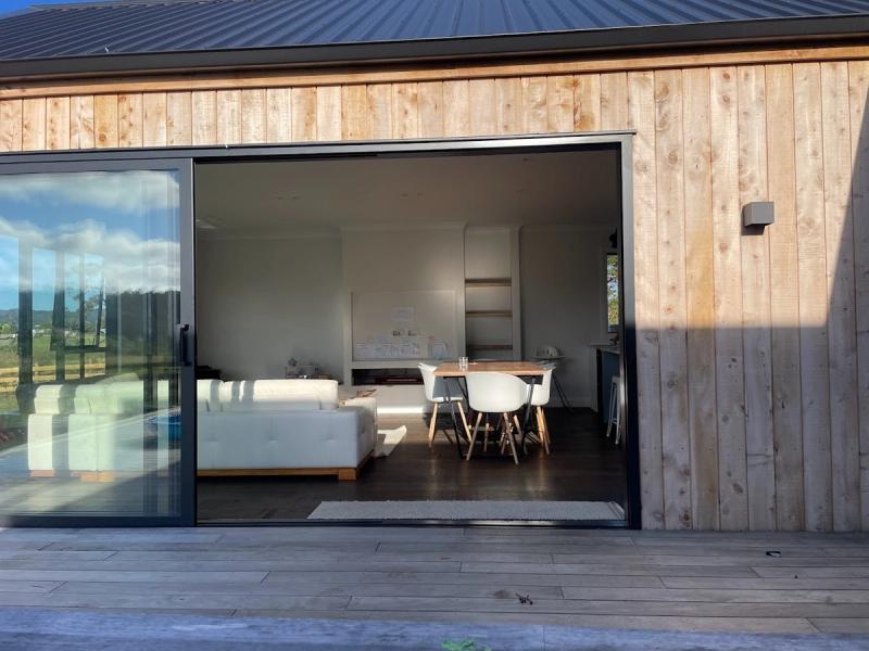 Full height sliding doors set into vertical timber cladding, open to the living room