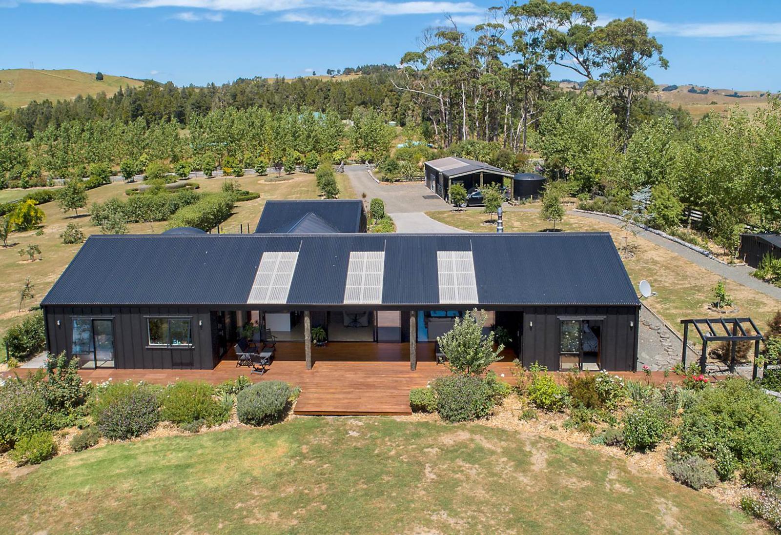 Aerial view of the single level home with solar panels, in rural Wainui