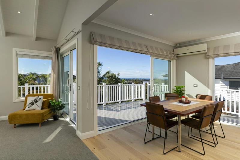 Dining area opening to the deck, with a harbour view beyond