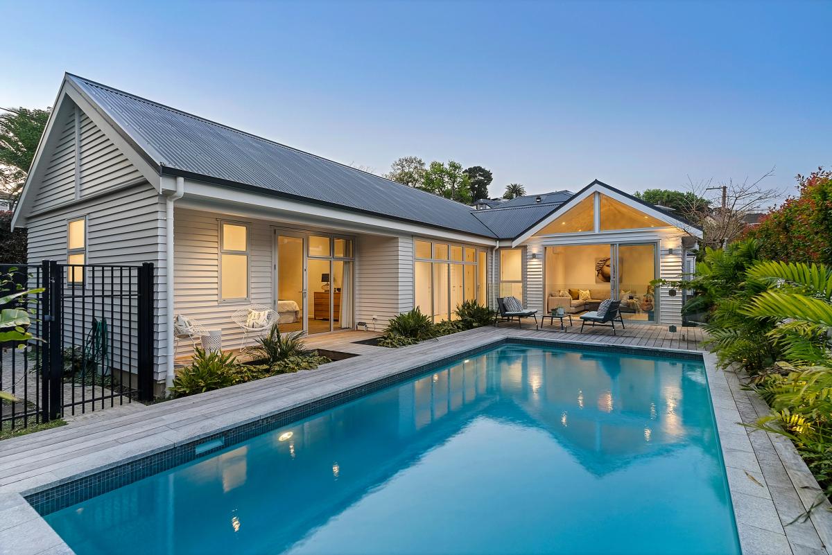 The extension lit at dusk, its gabled roofline reflected in the pool