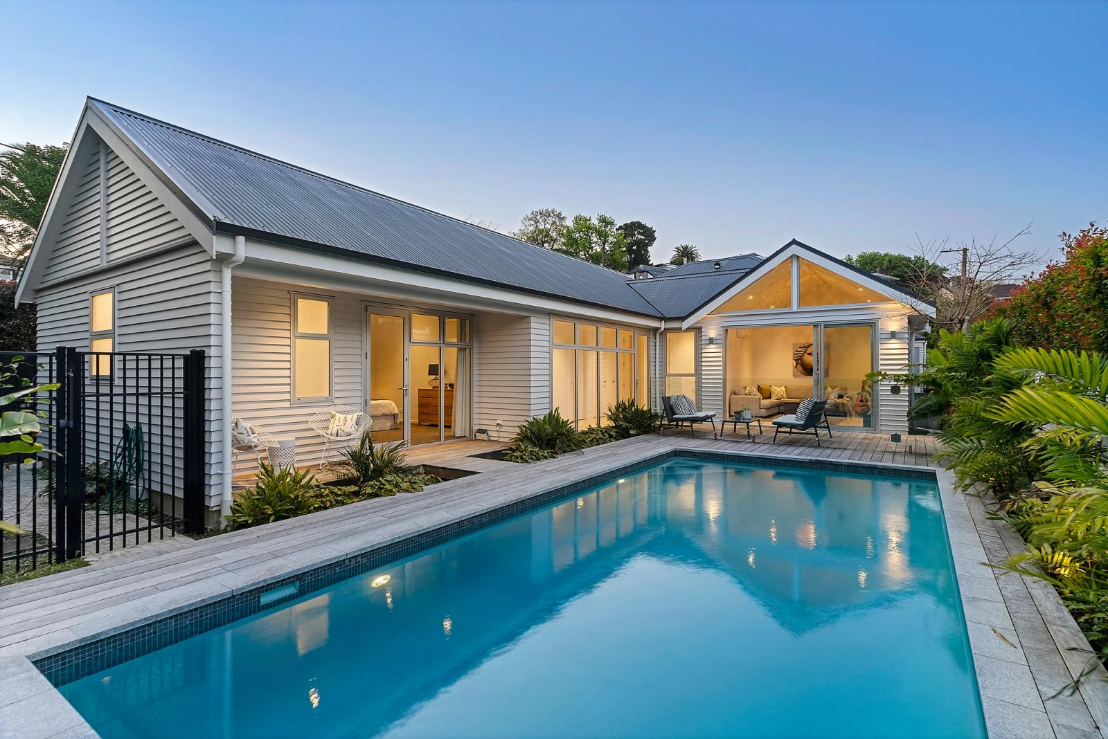 The extension lit at dusk, its gabled roofline reflected in the pool