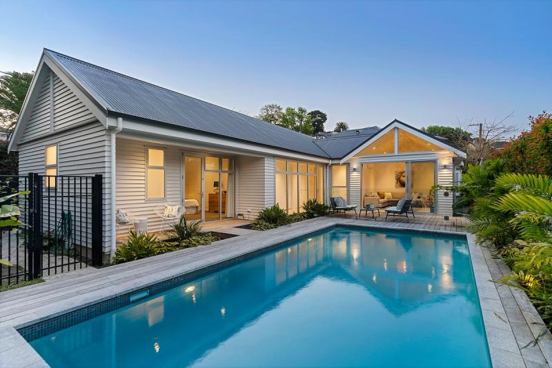 The extension lit at dusk, its gabled roofline reflected in the pool