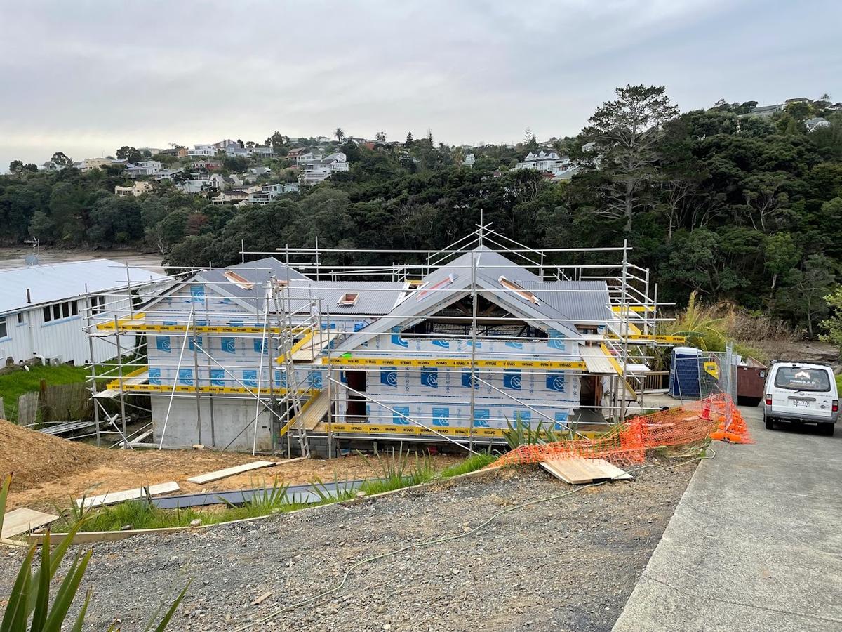 The house wrapped in building paper with scaffolding and the roof on