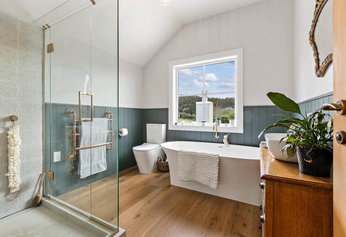 Bathroom with a freestanding bath, green panelling and a rural outlook