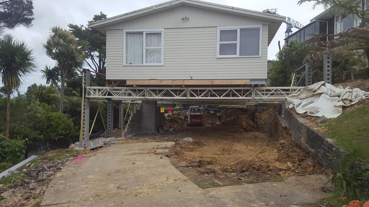 The house held on temporary steel props while the new lower level is dug out