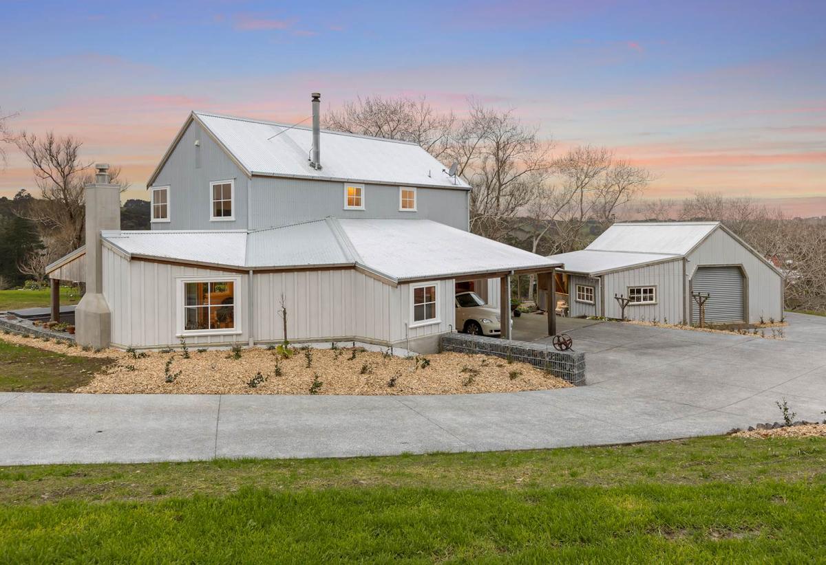 The house and separate garage at dusk, with a curved concrete driveway