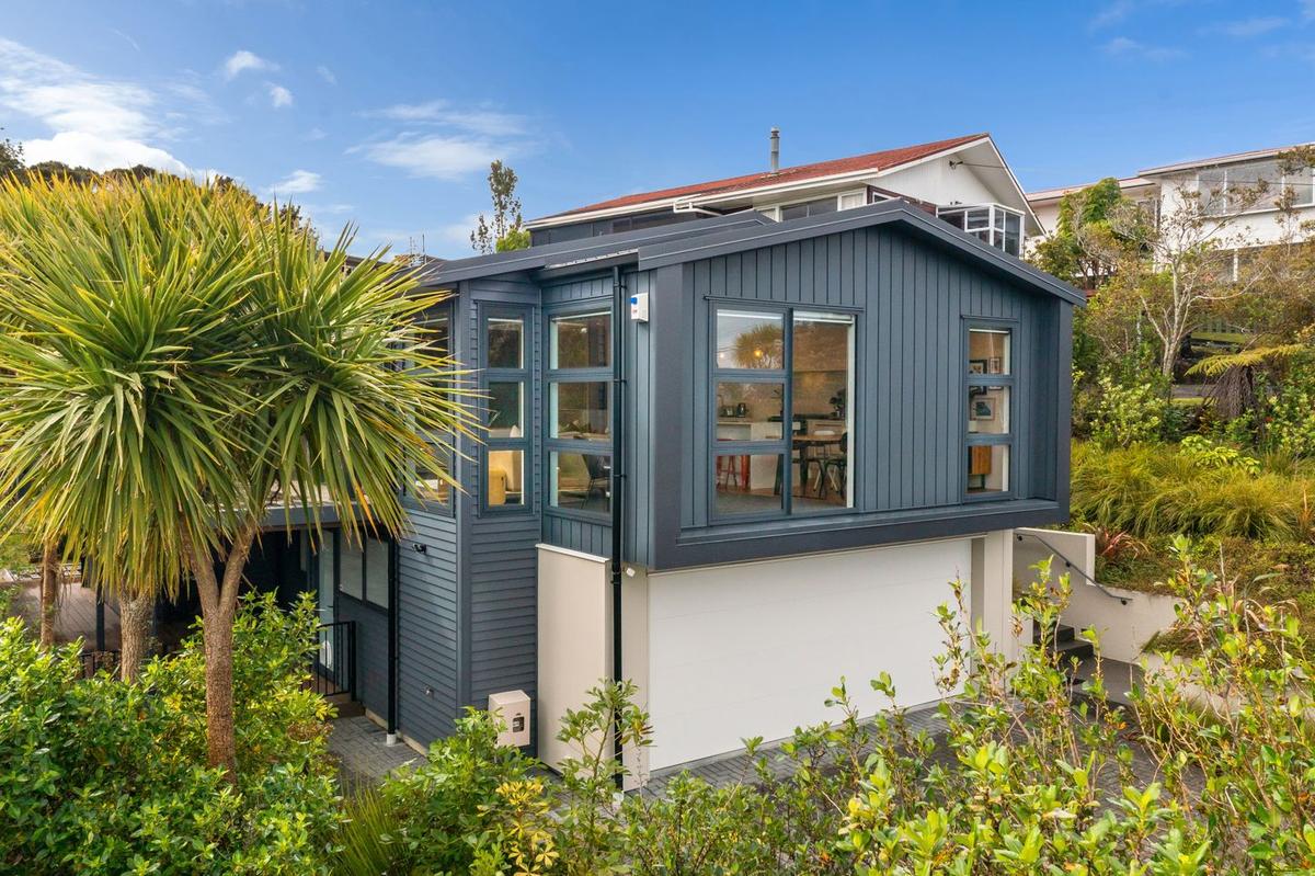 Corner of the house in dark blue cladding, with full height windows