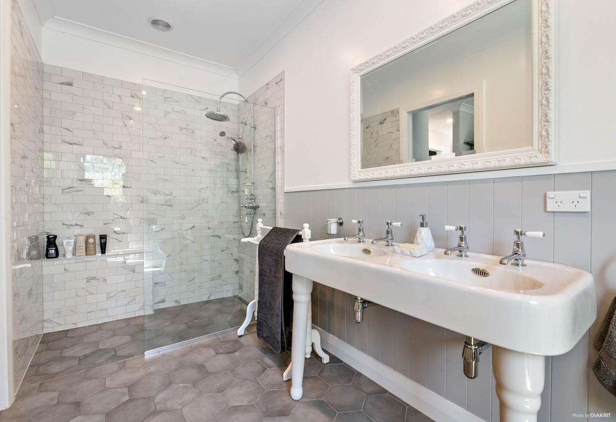 Twin pedestal basins beside a marble tiled walk in shower