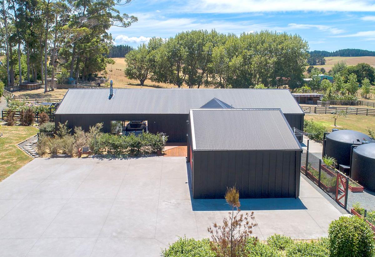 Rear of the house in dark cladding, with garage and water tanks