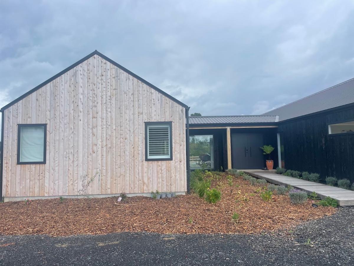 Timber clad gable end meeting the black cladding of the main wing