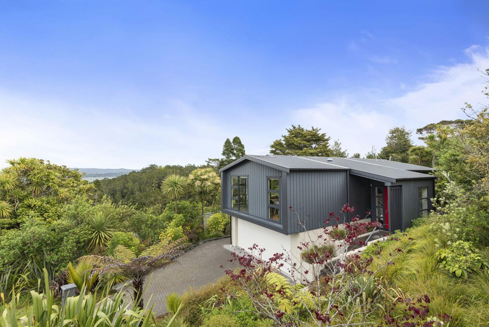 The finished home in dark cladding, set among native bush