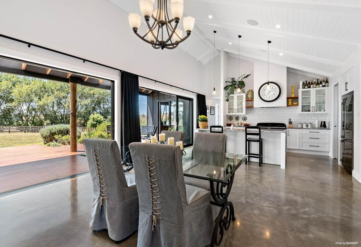 Dining area under a wrought iron chandelier, opening to the deck