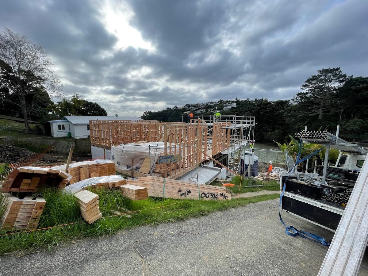 Framing underway on the sloping site, with the inlet behind