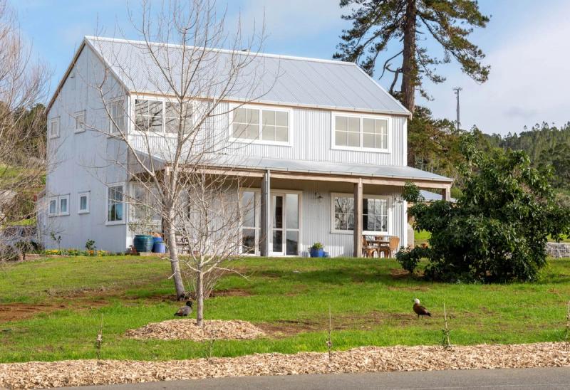 Barn style two storey home in white cladding, with a wide covered verandah